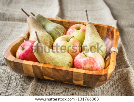 pears and apples in a wooden basket at a jute sack