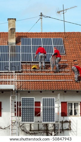 three worker installing solar panels on roof