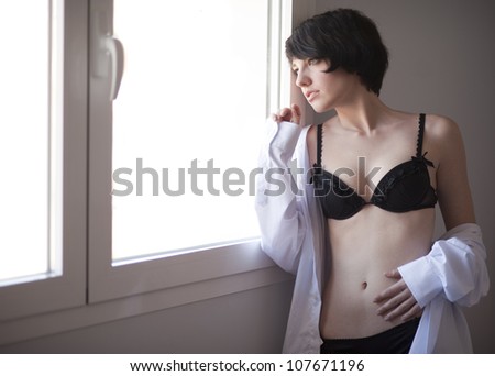 Pretty brunette looking at window in sexy lingerie and man shirt