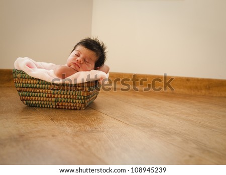 Baby sleeping on a basket on the floor over a blanket