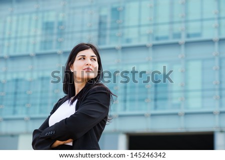 Young hot businesswoman with crossed arms in front of a building with a copyspace to the left