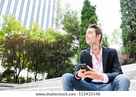 Young Entrepreneur Looking Away And Smiling Sit On Stairs. Focus On His Face