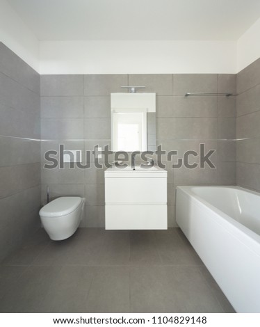 Modern bathroom with large tiles in newly built apartment. Nobody inside