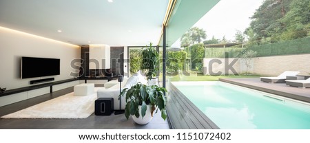 Modern living room overlooking the garden and swimming pool. Nobody inside