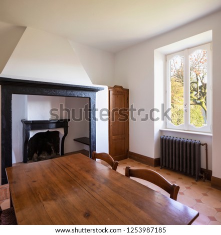 Dining room with table, wooden chairs and a stone fireplace. Nobody inside