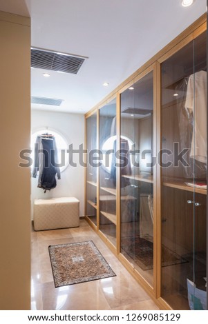 Walk-in closet in wood and marble with large round lighted window. Nobody inside