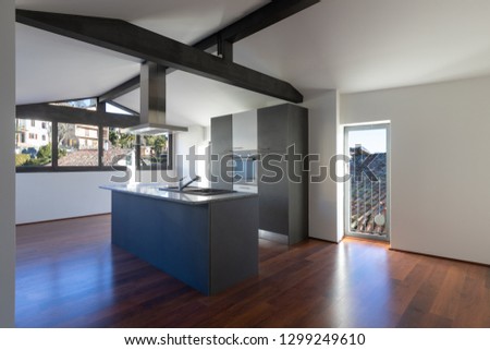 Modern kitchen island in a renovated apartment with a dark colored wooden floor. Everything is empty and there is no one inside