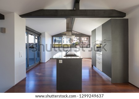 Modern kitchen island in a renovated apartment with a dark colored wooden floor. Everything is empty and there is no one inside