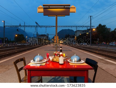 laid table for two persons on the sidewalk of a train station, outdoors