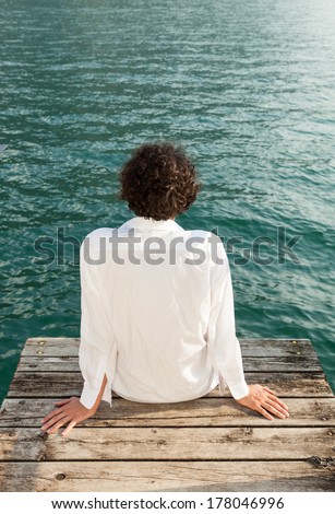 portrait of young man on the dock of Lake, rear view