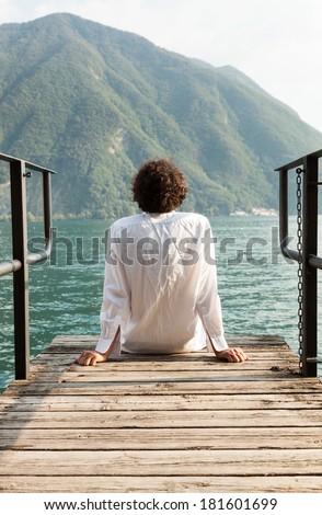 portrait of young man on the dock of Lake, rear view