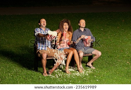 three friends watching a movie at cinema outdoors