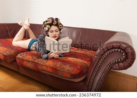 portrait of a model with a book, lying on the sofa
