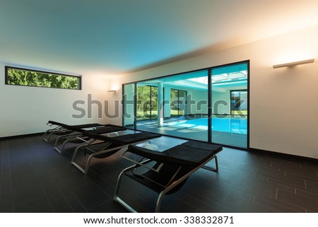 indoor swimming pool of a modern house with spa, room with sunbeds