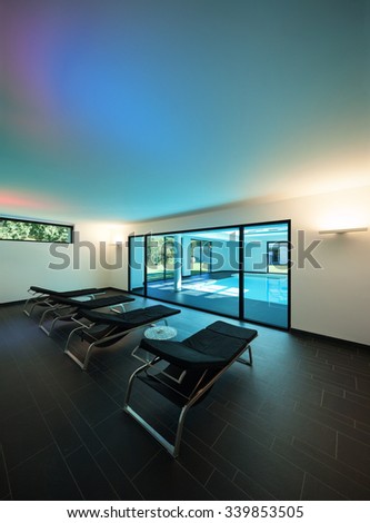 indoor swimming pool of a modern house with spa, room with sunbeds