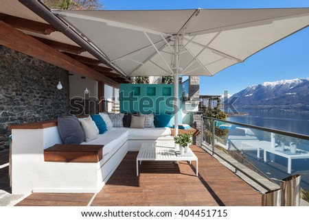 Terrace lounge with comfortable divans and lake view in a luxury house