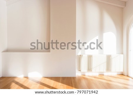 Completely white wall, light enters the large windows. Nobody inside