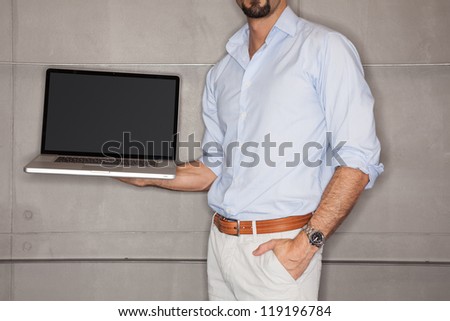 Man in office showing his presentation on laptop - landscape interior.
