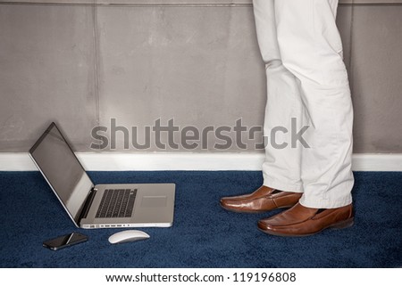 Man standing with laptop in office - landscape interior.