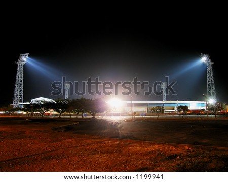 Illuminated stadium at night from parking lot.