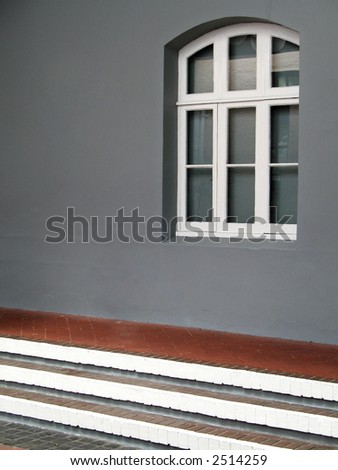 Portrait photo of a colonial window in a gray wall.