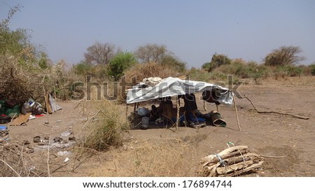 MINGKAMA, AWERIAL, LAKES STATE, SOUTH SUDAN - 2014 JANUARY 27 - One family lives under a piece of plastic sheeting after it fled from Bor