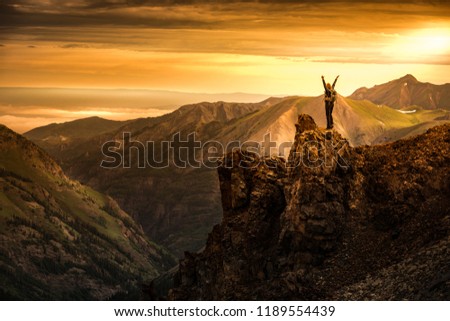 Young Woman Backpacker in Victory Pose with raised up arms on top of the Mountain Colorado USA