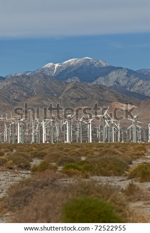 Wind Turbine farm located on California desert surrounded by mountains.