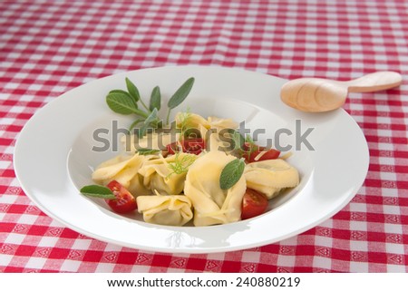Tortellini in plate on red checked tablecloth