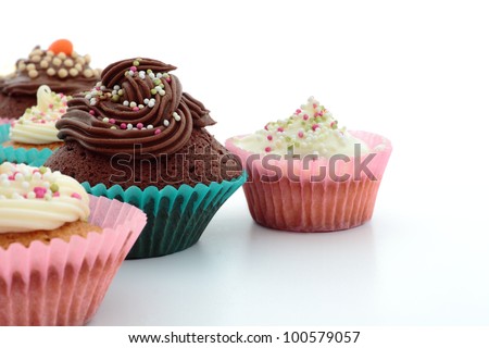 Homemade cupcakes, or fairy cakes, with buttercream  in blue and pink cups with a white background
