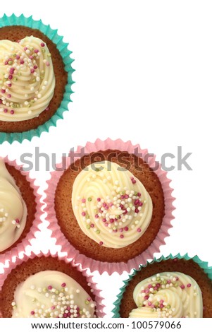 Homemade cupcakes, or fairy cakes, with buttercream and sprinkles in blue and pink cups with a white background