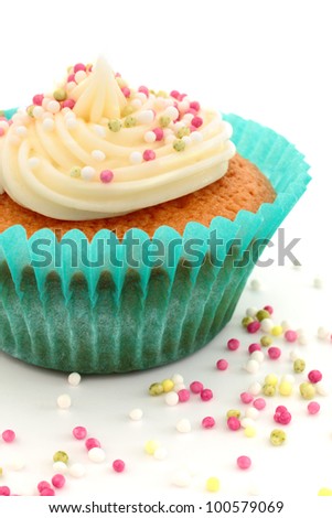Homemade cupcake, or fairy cake, with buttercream and sprinkles in a blue cup with a white background