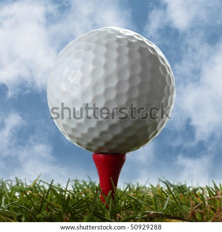 Golf ball on a red tee with cloudy blue sky behind