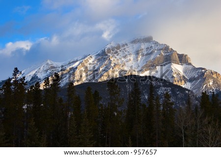 A peak in the Rocky Mountains lit with sunrise light on a winter morning.