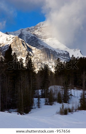 A peak in the Rocky Mountains lit with sunrise light on a winter morning.