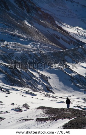 A single person hikes into the distance in snow covered mountains.
