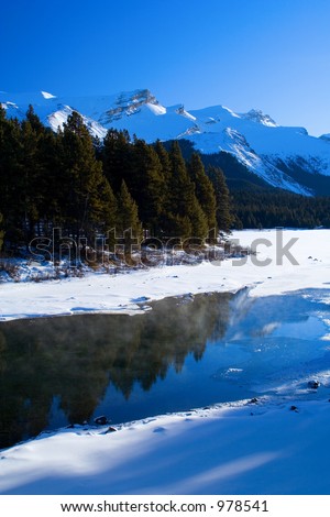 A cool scene mountain scene featuring open water in mid winter.