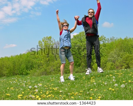 A couple jumps for joy in a meadow