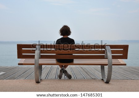 Loneliness Teenager Sitting On A Bench At The Sea Shore