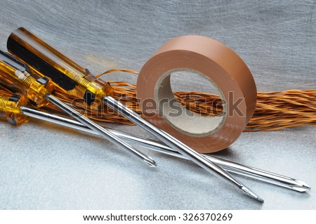 Screwdrivers insulating tape and cables on metal surface with place for text