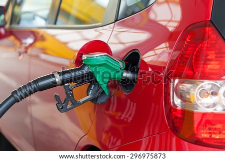 Red car at gas station being filled with fuel