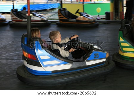 Boy and a girl having a ride in the bumper car at the fun fair