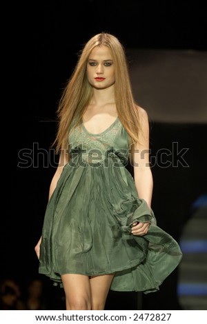 Fashion model in green toned dress walking down the runway
