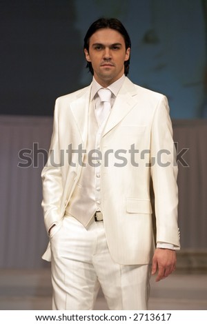Young man in classic, elegant white suit holding one hand in pocket