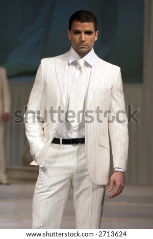 Young man in classic, elegant white suit and black belt