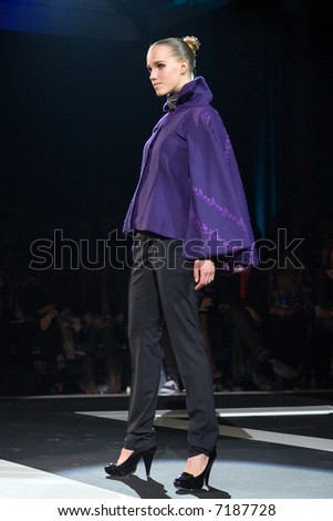 Fashion model in purple shirt and black trousers on a catwalk