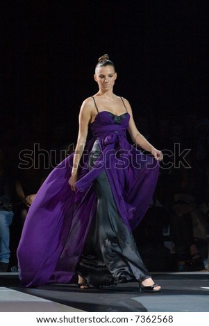 Fashion model in a long purple gown walking down the runway