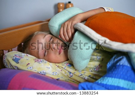 Young boy sleeping in bed with his favorite toy