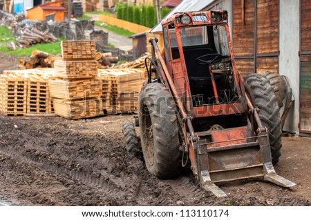 Wood industry outdoors, with red tractor