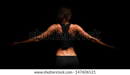 Upper body of a muscular woman from the back in a studio